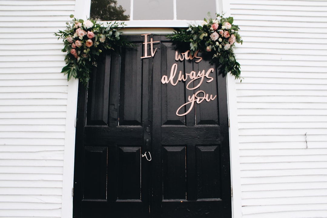 Dark wooden door with floral decorations and the phrase "It was always you" in cursive, suitable for a rustic or romantic setting.